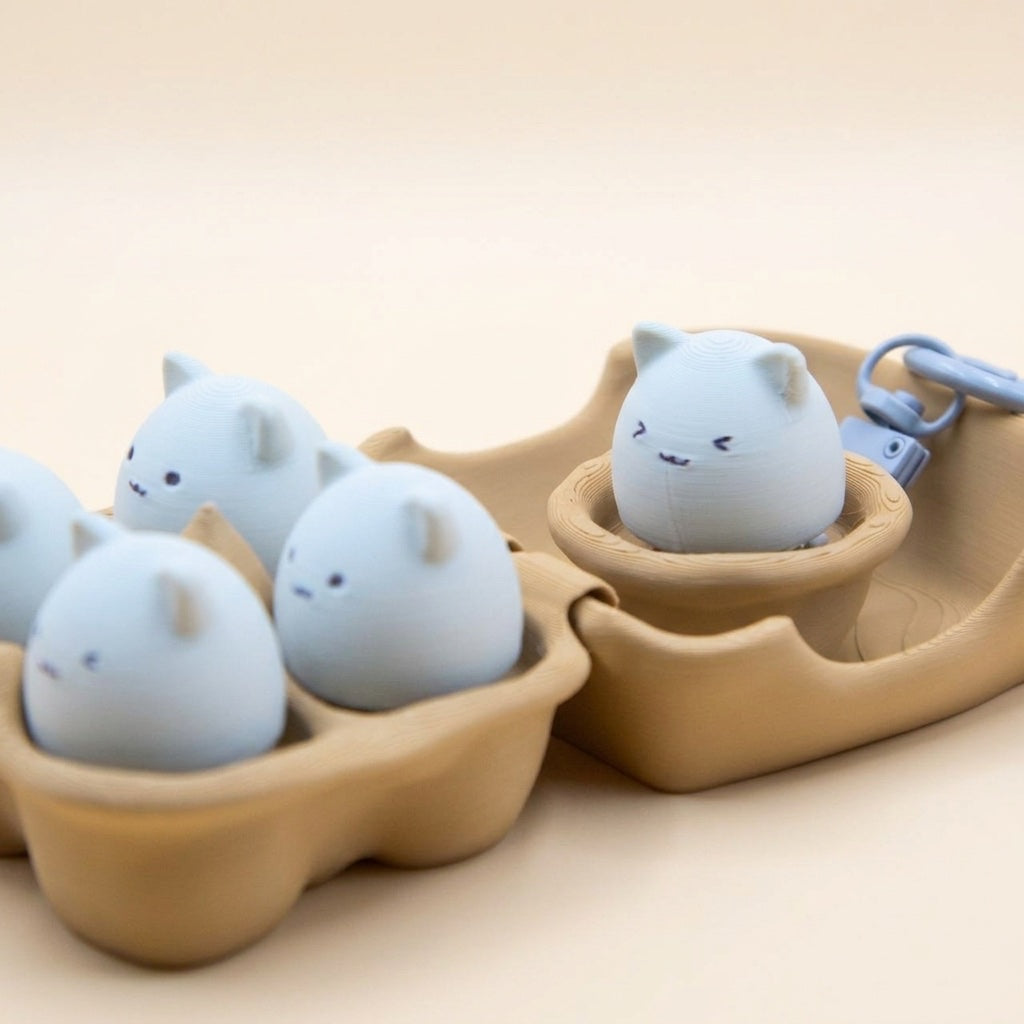 Egg MEOW Family bundle with mini egg-shaped cat figurines in carton and hatchling keychain cradle